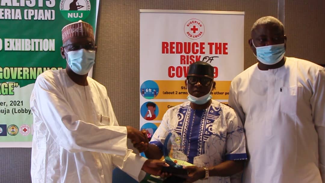 (Middle) Mr. Gabriel Odu, NIDCOM Media, receives Award of Excellence on behalf of Hon. Abike Dabiri-Erewa, Chairman/ CEO, (NIDCOM) at PJAN PHOTO EXHIBITION in Abuja. He is flanked by (L) Mohammed Borno, Chief of staff to FCT Minister and (R) Mr. Abayomi Fayese, PJAN Chairman.