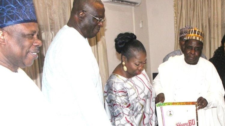 Senator Ibikunle Amosun, Mr Segun Erewa with his wife, Hon. Abike Dabiri-Erewa, receiving a birthday card and a cake from Engr Dr Sule Yakubu Bassi, Secretary of NIDCOM, on behalf of the Staff and Management of the Commission to celebrate the 60th birthday of its CEO in Abuja.